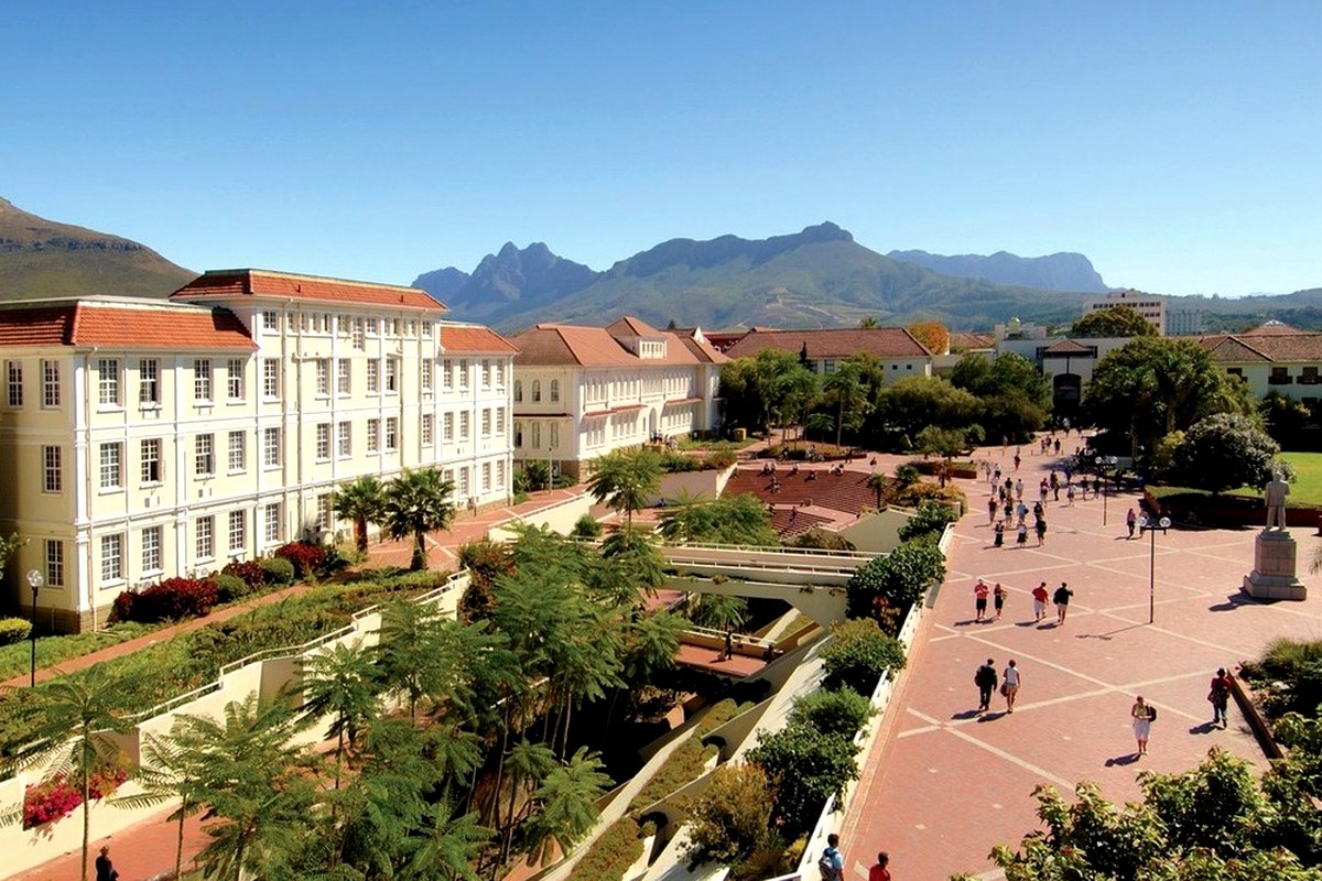 A landscaped garden and campus buildings with mountains in the distance.
