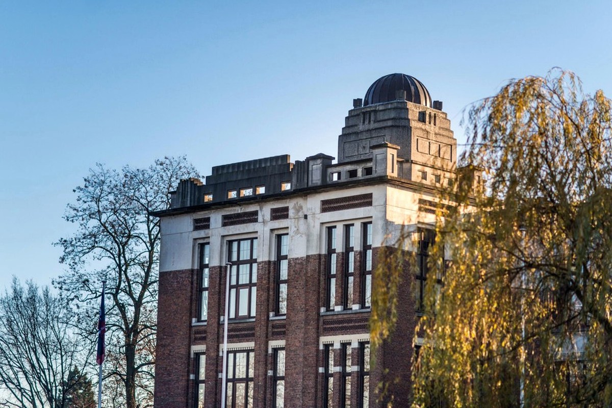 An older multi-storey building framed by trees in autumn light.